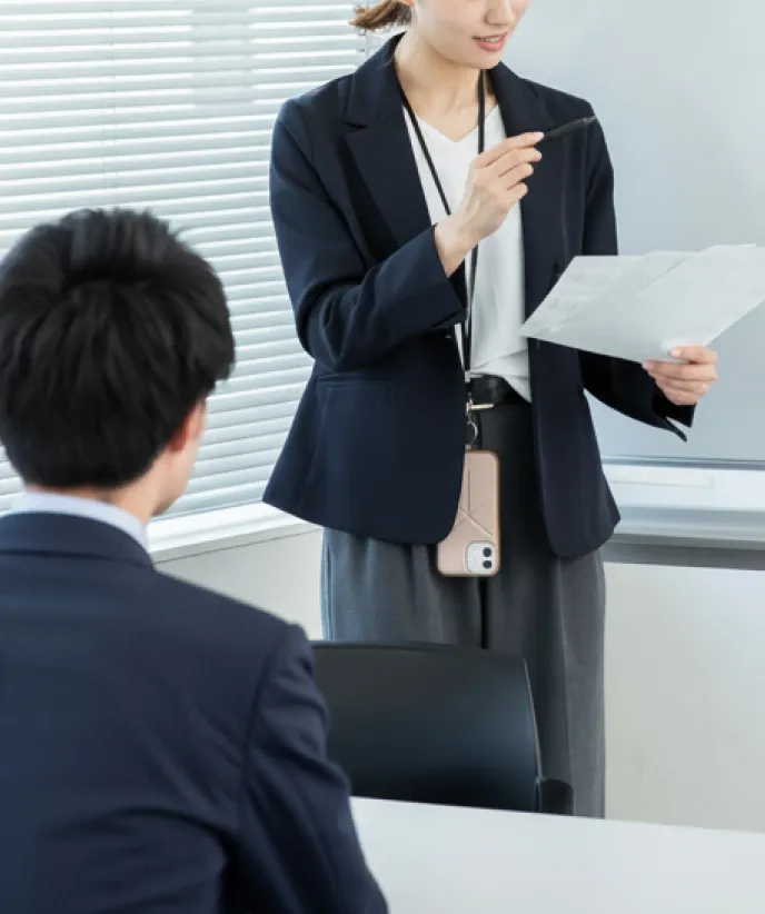 資料を手に説明する女性社員と話を聞く男性社員