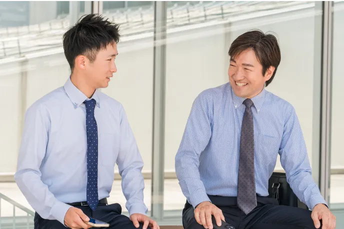 打ち合わせ中に笑顔で会話する男性社員2人