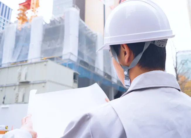 建設現場で図面を確認する施工管理担当者