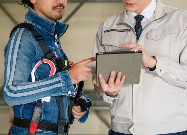 建設現場でタブレットを使い打ち合わせを行うスタッフ