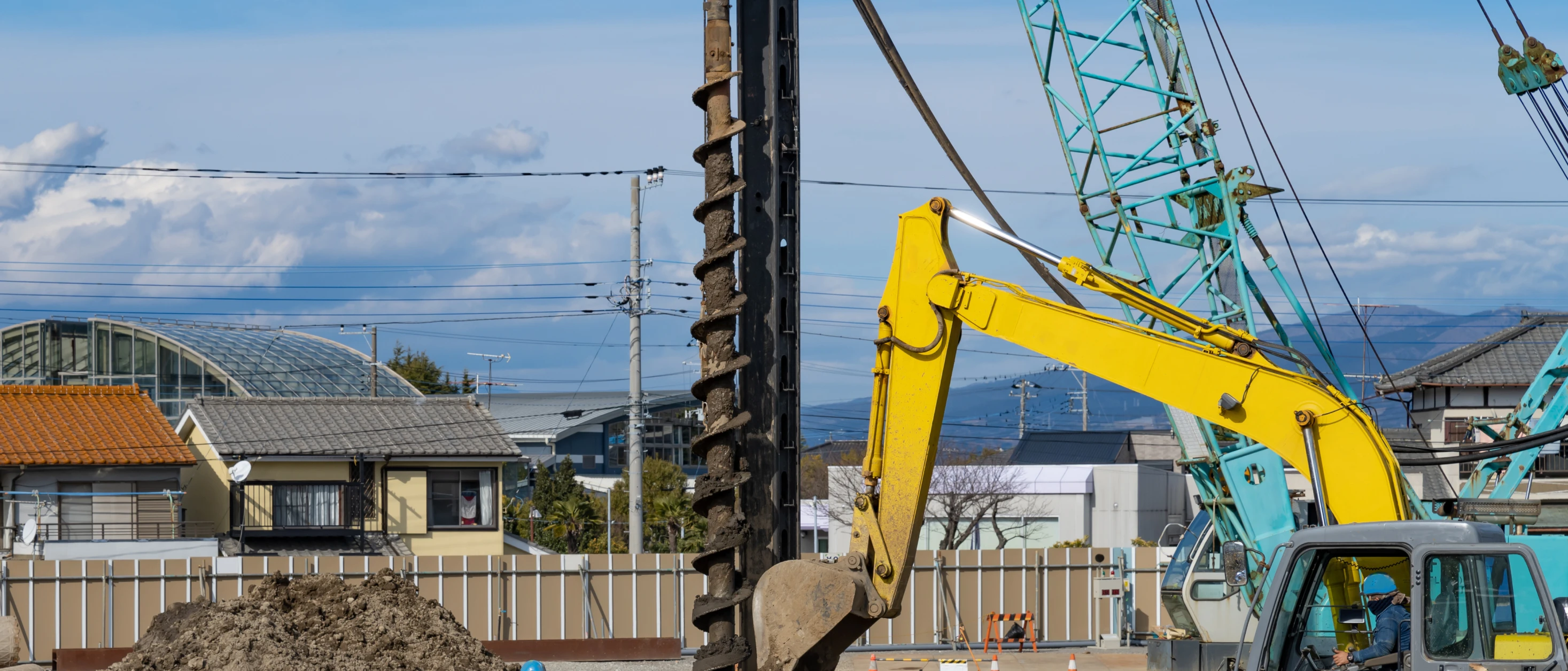 住宅地の造成現場でアースオーガーを使い地盤改良を行う重機