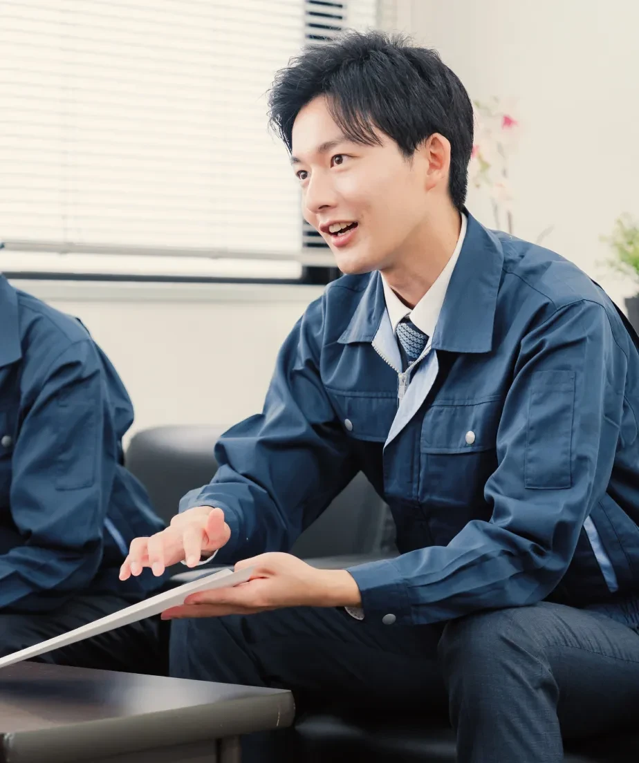 作業着姿で身振りを交えて話す若手社員