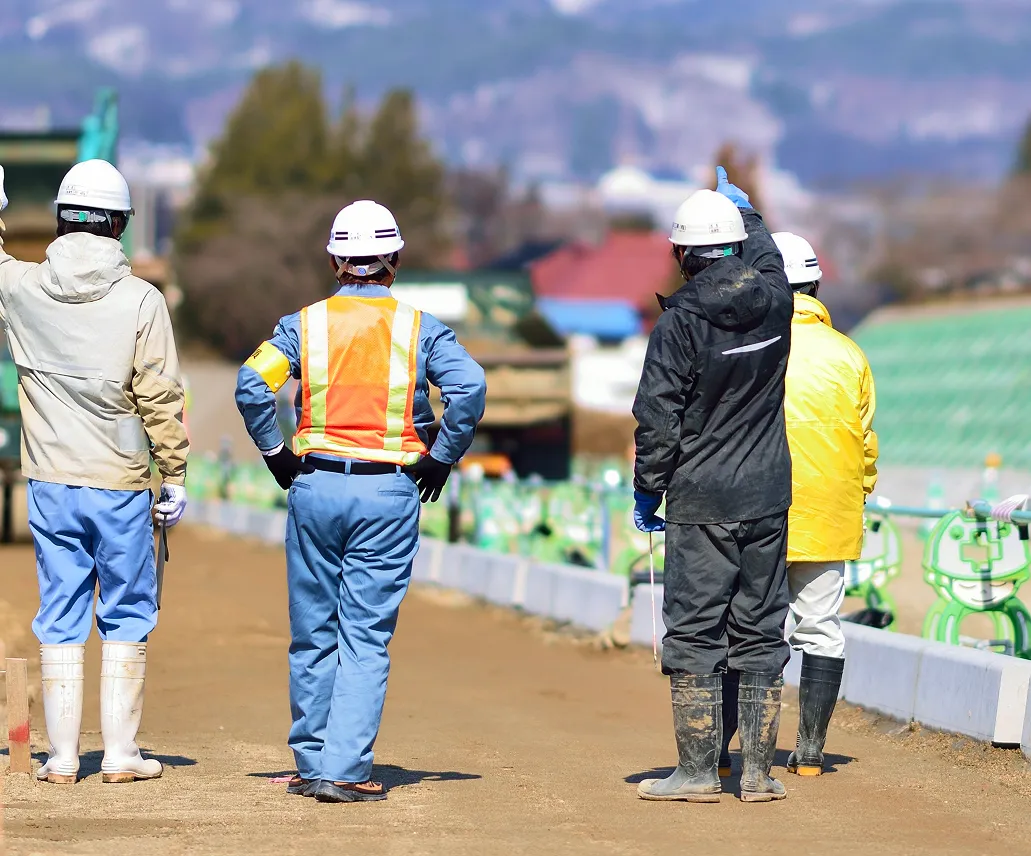 ヘルメットを着用した建設スタッフが現場で確認作業をしている様子